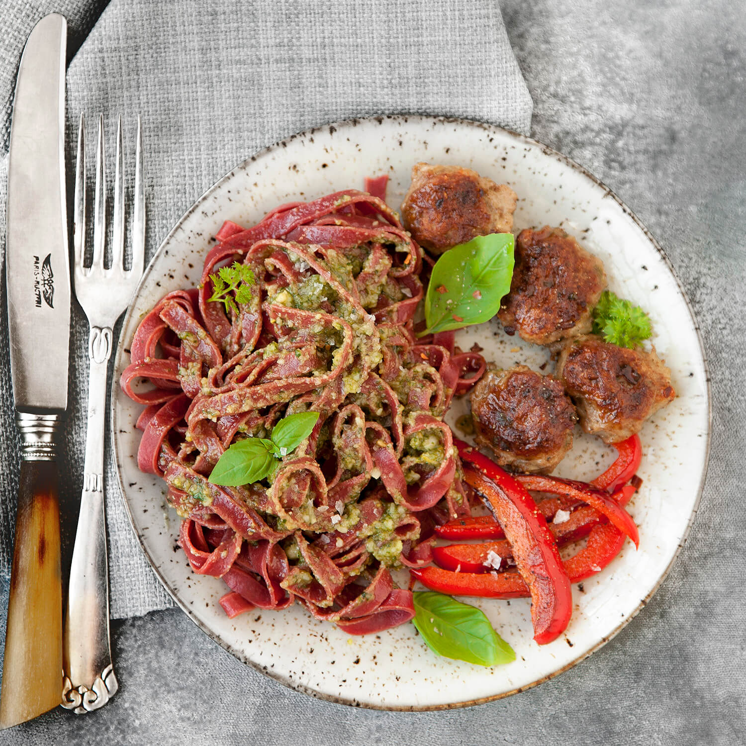 Pasta med rodfrugter, kødboller, grøn pesto, rød peber og friske krydderurter